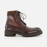 The DI BIANCO Torino Calfskin Suede Boot is shown in profile on a plain white background—a single, dark brown military-style boot, handmade in Italy, featuring a thick rubber sole, quilted fabric around the ankle, and detailed stitching.