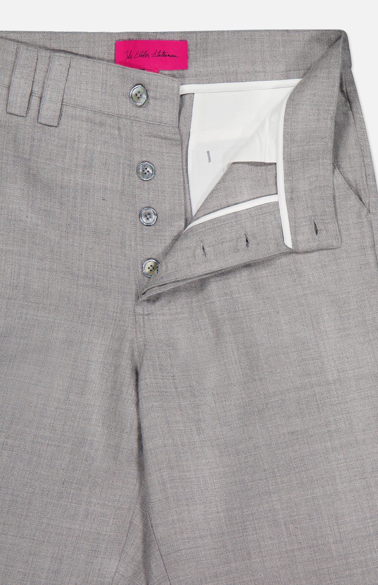 The Pashmina Norm Pant by ELDER STATESMAN is crafted from light gray wool-cashmere with a fine, smooth texture for an elegant look. These men's dress pants feature a partially open button fly that reveals a white inner lining, as well as a waistband with belt loops and a pink label sewn inside.