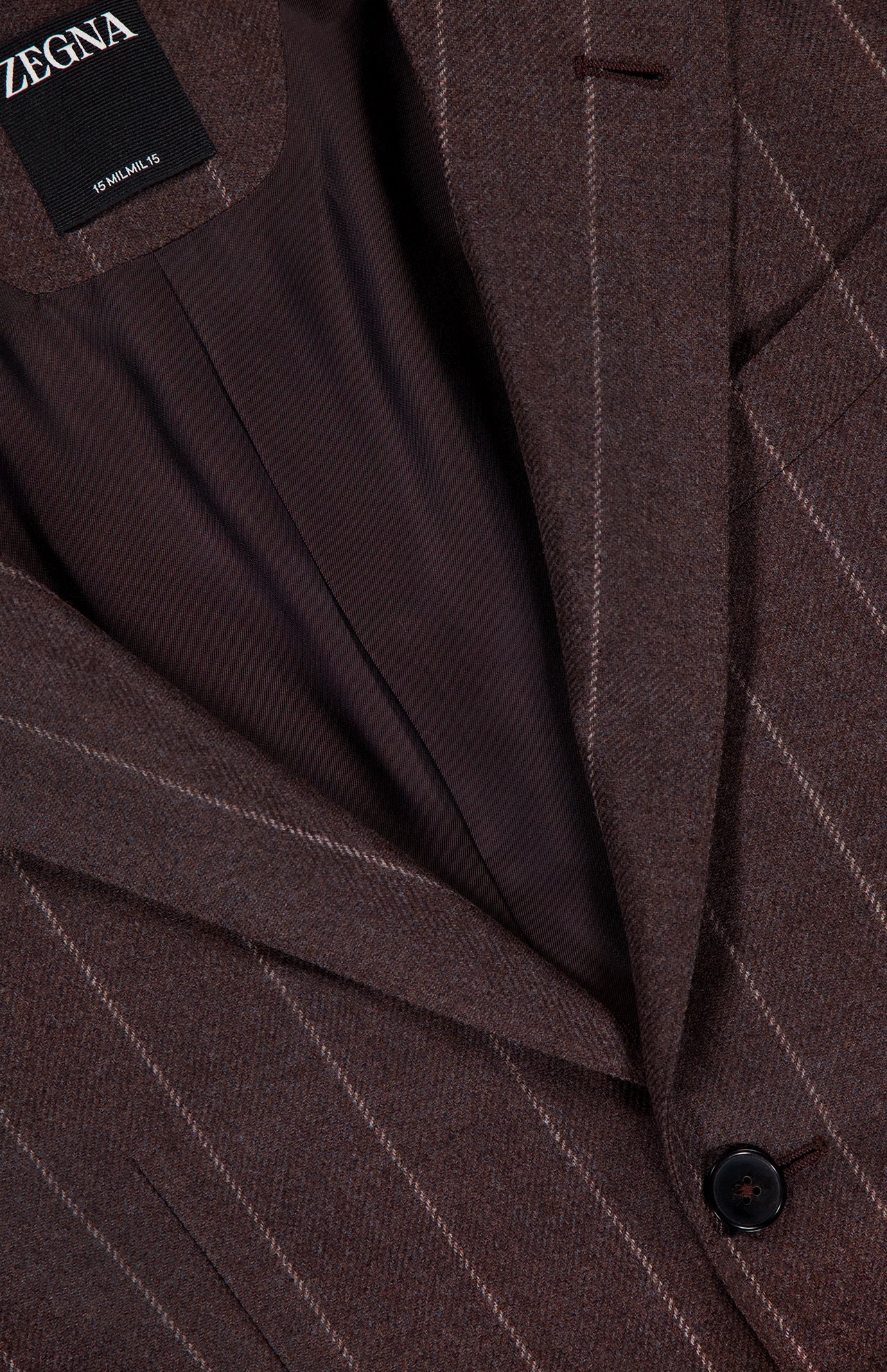 Close-up of the ZEGNA 15MilMil15 Wool Pinstripe Suit jacket in dark brown, featuring pinstripes, a notched lapel, single black button, visible inner lining, and a brand label that showcases expert Italian craftsmanship.
