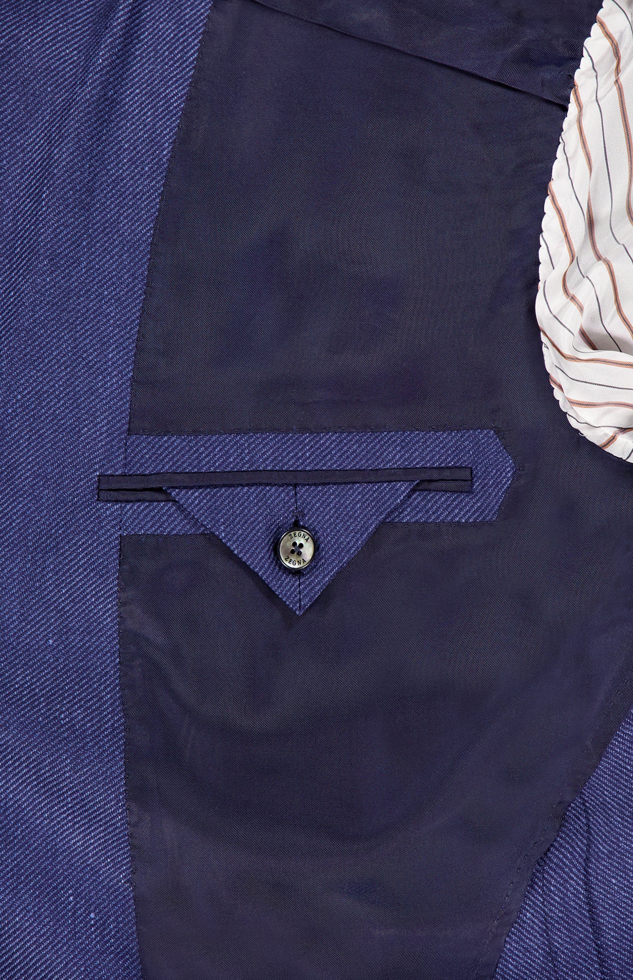 Close-up of the inside pocket of the ZEGNA Cashmere Silk Linen Sportcoat in dark blue, showing a blue herringbone fabric, dark pocket flap button, and striped lining. Expertly crafted in Italy for refined style.
