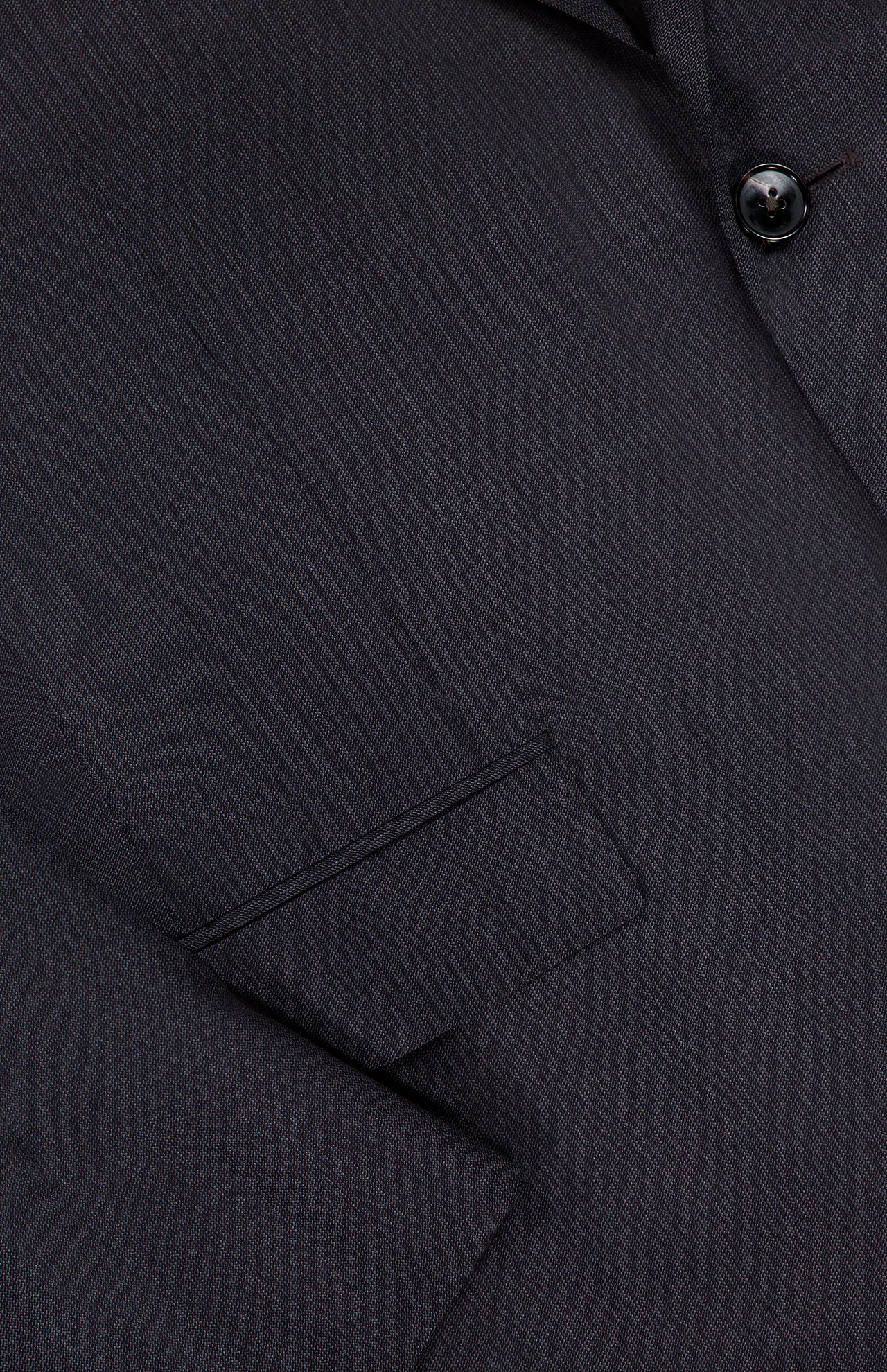 Close-up of the ZEGNA 15MilMil15 Wool Suit jacket in dark grey, made in Italy, featuring a textured fine-patterned fabric, a flap pocket, part of the lapel, and a single button.
