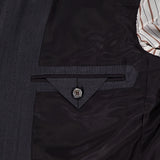 Close-up of the ZEGNA 15MilMil15 Wool Suit's dark grey interior lining, made in Italy, showing a neatly stitched pocket with a triangular flap and button. A striped fabric lining is visible on the right.