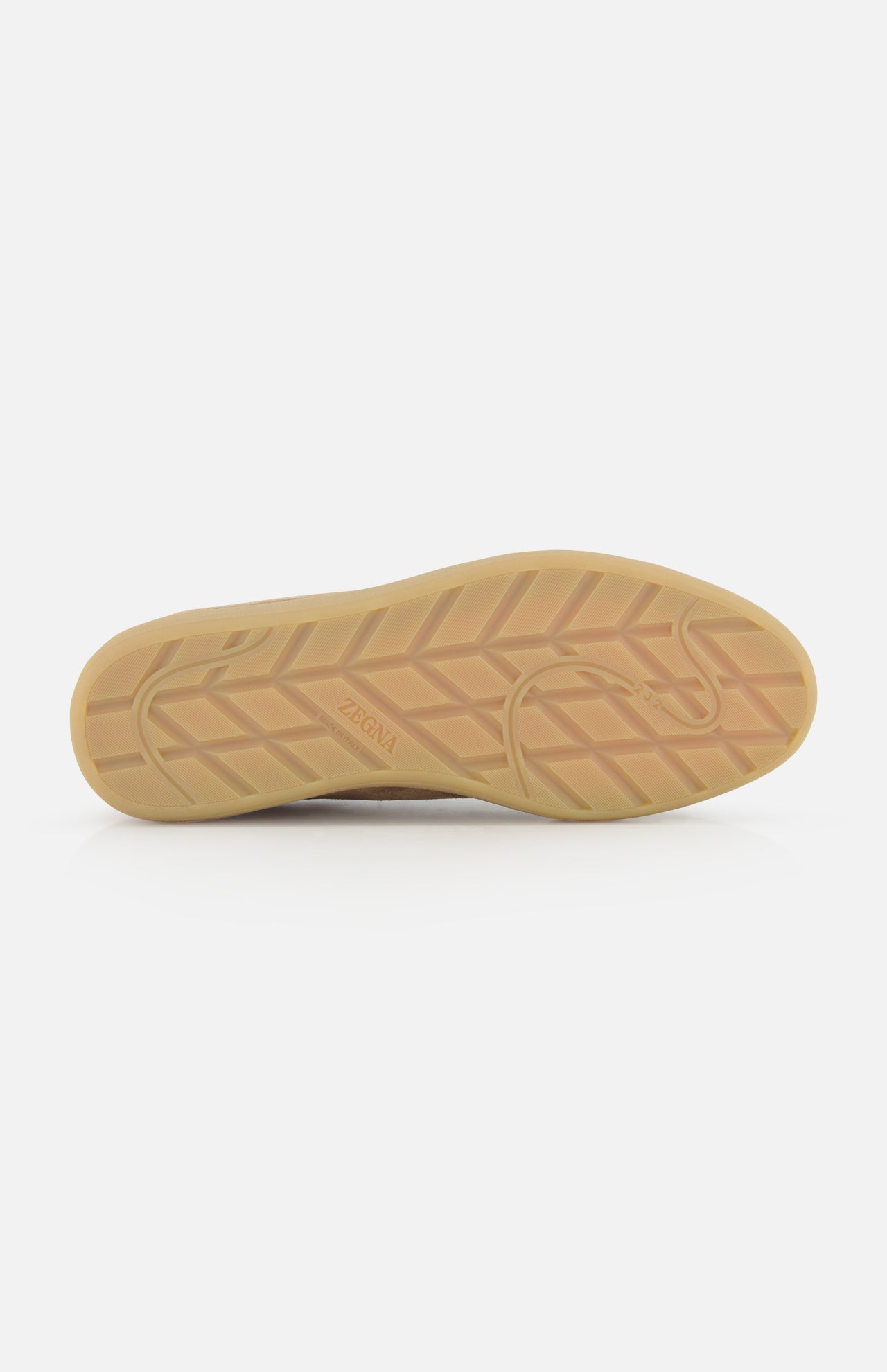 The image displays the bottom of the ZEGNA 232 Low Top Sneaker, showing a tan rubber sole with a geometric tread and ZEGNA branding at the center, complemented by dark tan suede accents.