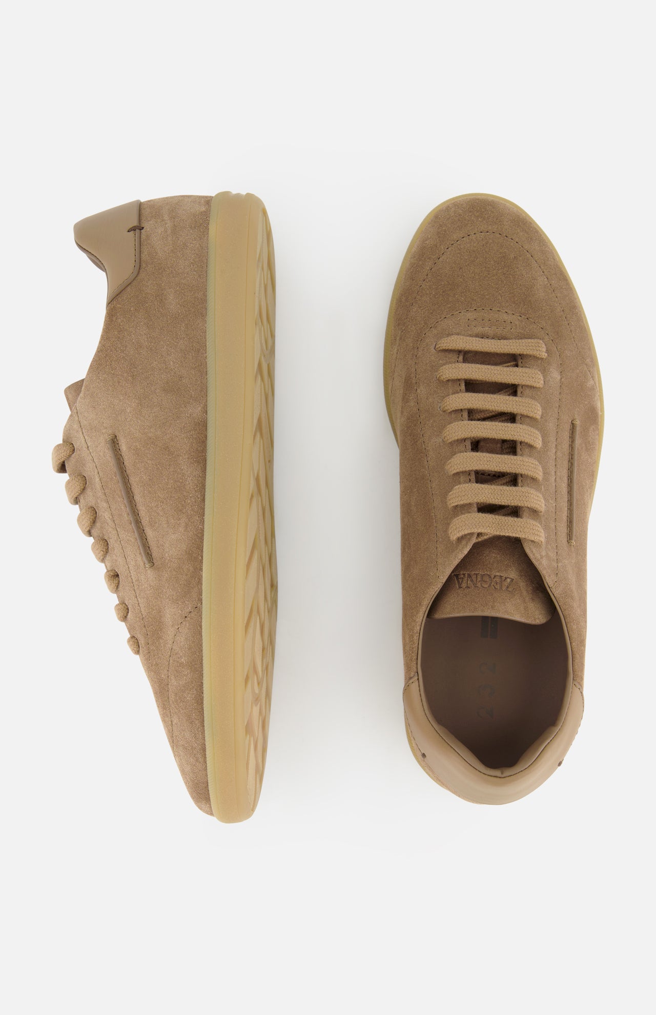The ZEGNA 232 Low Top Sneakers in dark tan suede with tan rubber soles are displayed on a white background—one shown from the side to highlight the sole and profile, the other viewed from above emphasizing the laces.