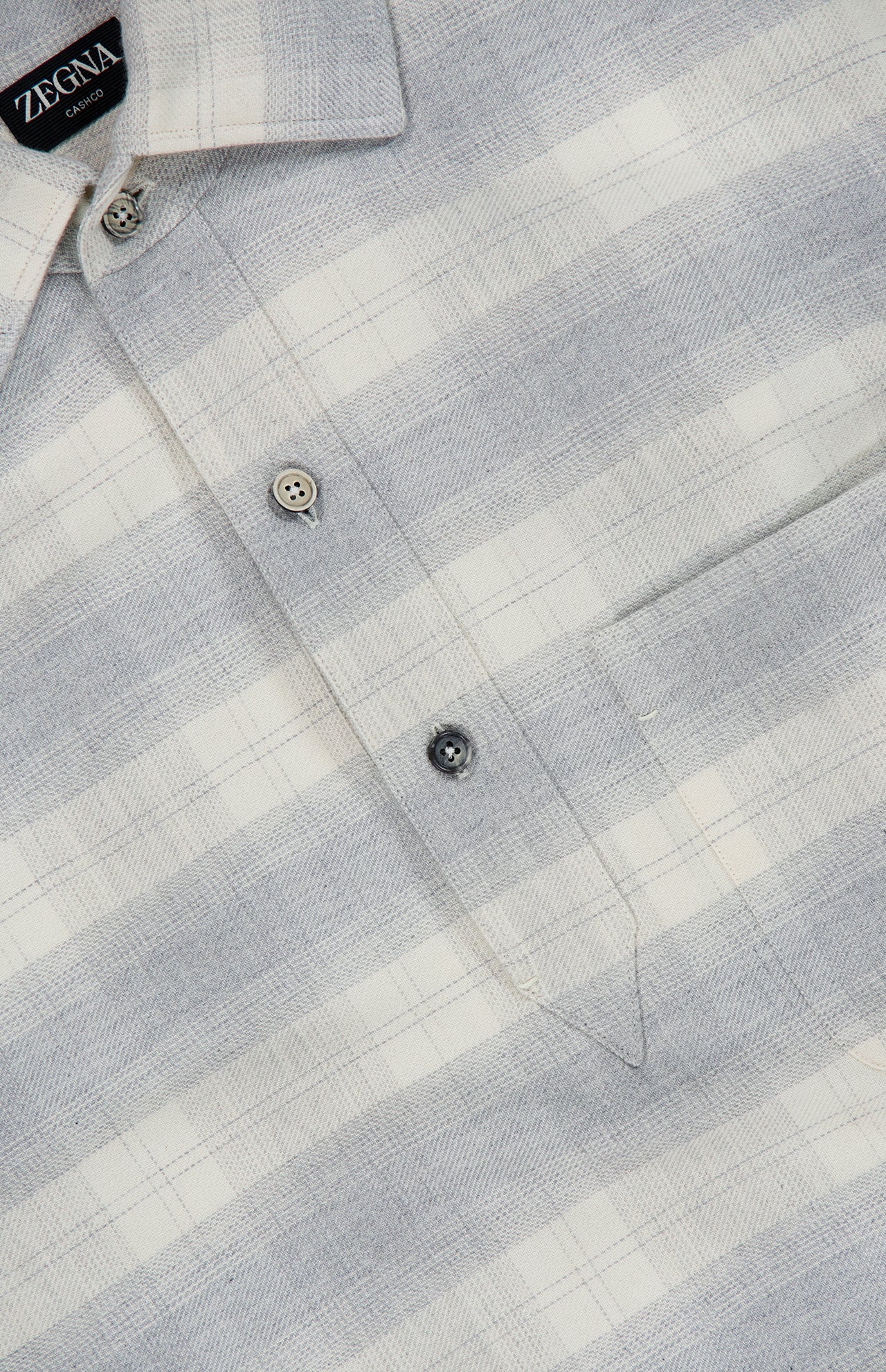A close-up of a ZEGNA Cashco Flannel Shirt showcasing a light gray and white plaid pattern, partial button placket, and chest pocket.