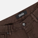 Close-up of the waist area of ZEGNA Comfort Linen Cotton Pants in slim fit, dark brown, showcasing a visible ZEGNA label, belt loops, button closure, and detailed front pockets.