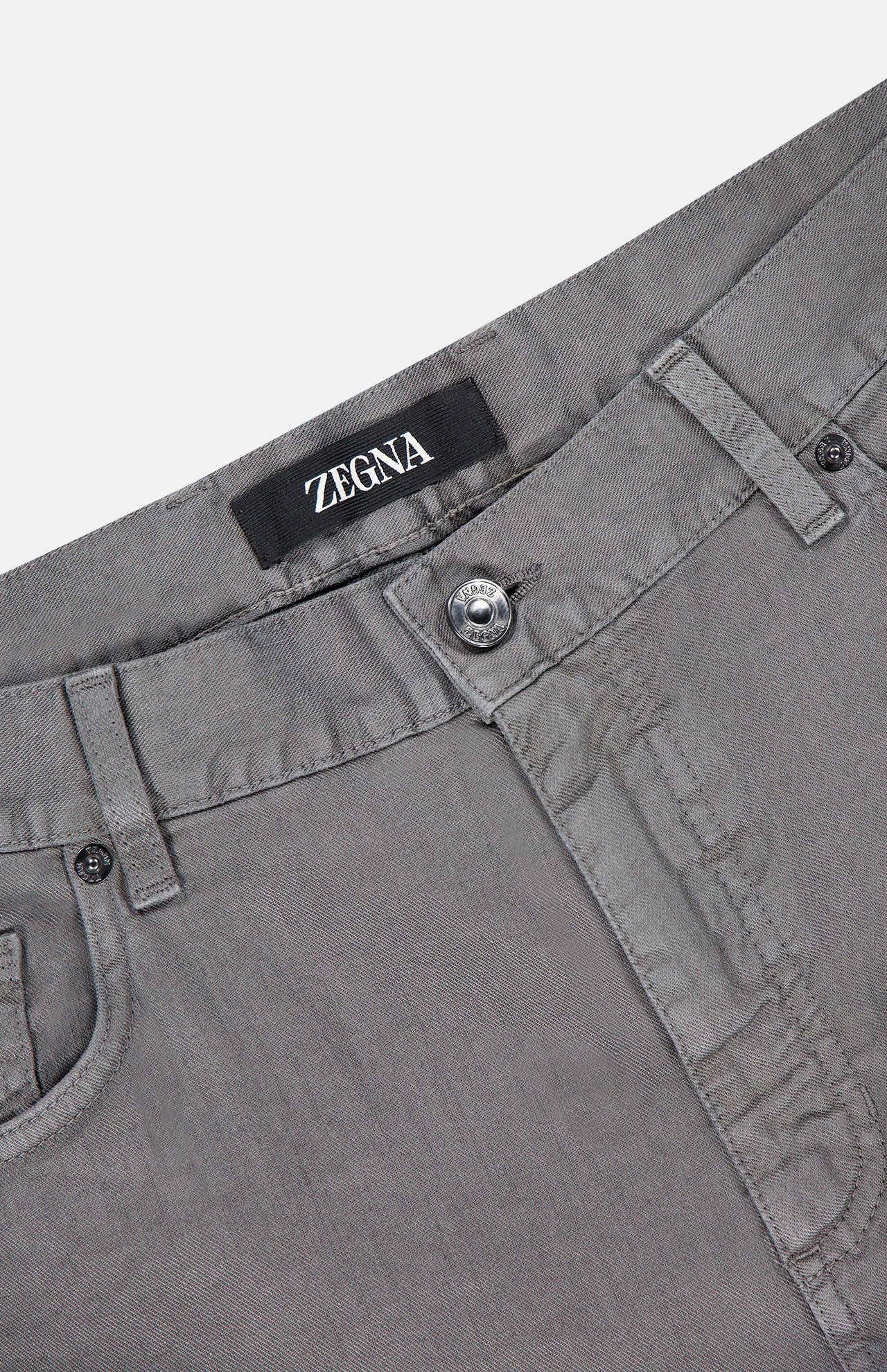 Close-up of the waistband and upper section of ZEGNA Comfort Linen Cotton Pants in gray, highlighting belt loops, a button closure, and the ZEGNA brand label on the inside.
