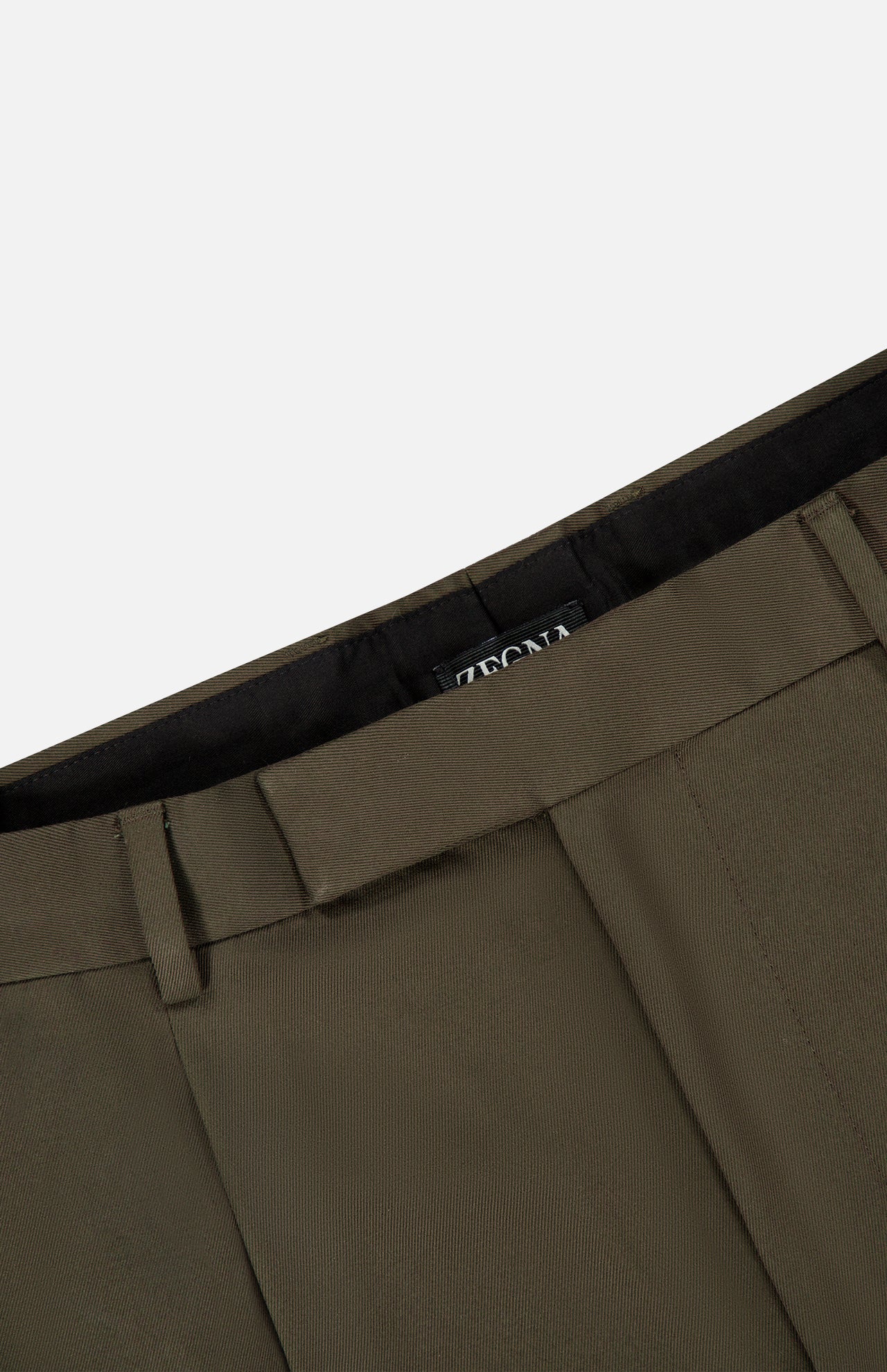 Close-up of the ZEGNA Cotton & Wool Trouser Pants in olive green, featuring the waistband, belt loops, and a partial view of a black interior label with white text. The fabric displays a smooth yet subtly textured finish, emphasizing the quality craftsmanship of these dark green trousers.