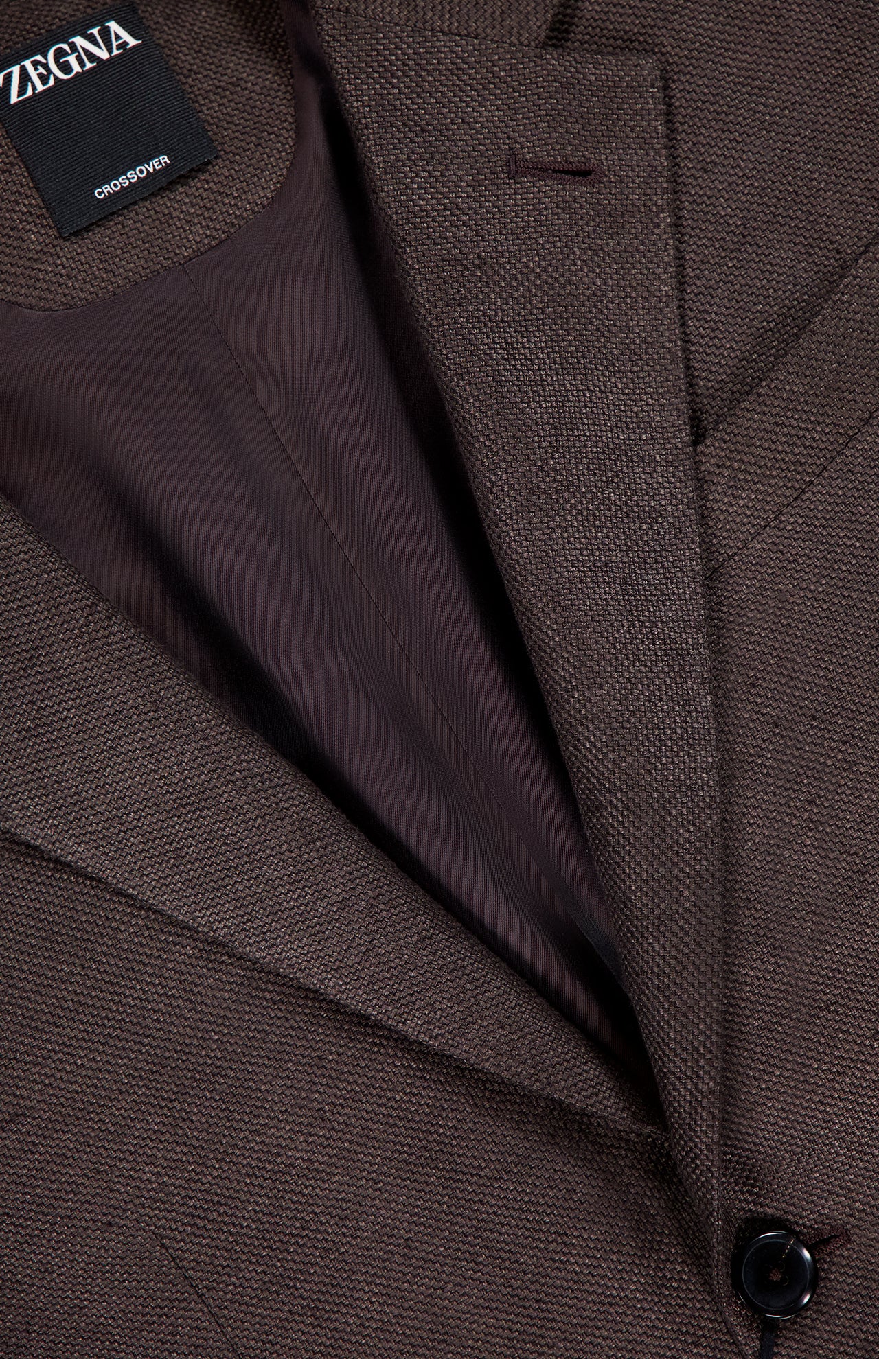 Close-up of the ZEGNA Crossover Linen and Wool Sportcoat in brown, featuring textured fabric, smooth dark brown lining, a black button, and an inner collar label reading ZEGNA and CROSSOVER.