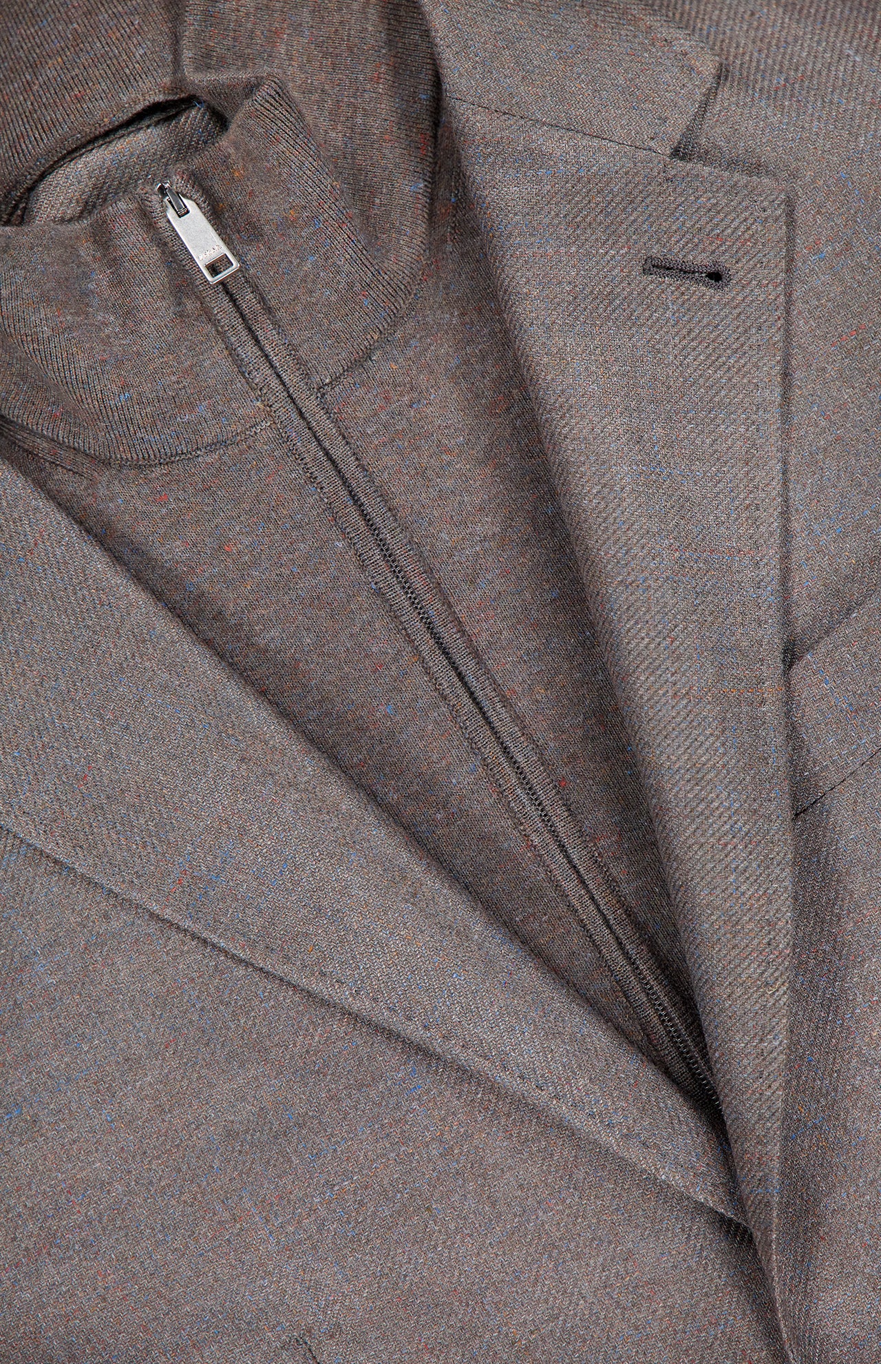 Close-up of the ZEGNA Detachable Knit Bib Sportcoat, featuring a brown men's luxury blazer layered over a matching zip-up knit bib, with highlighted zipper and lapel details.