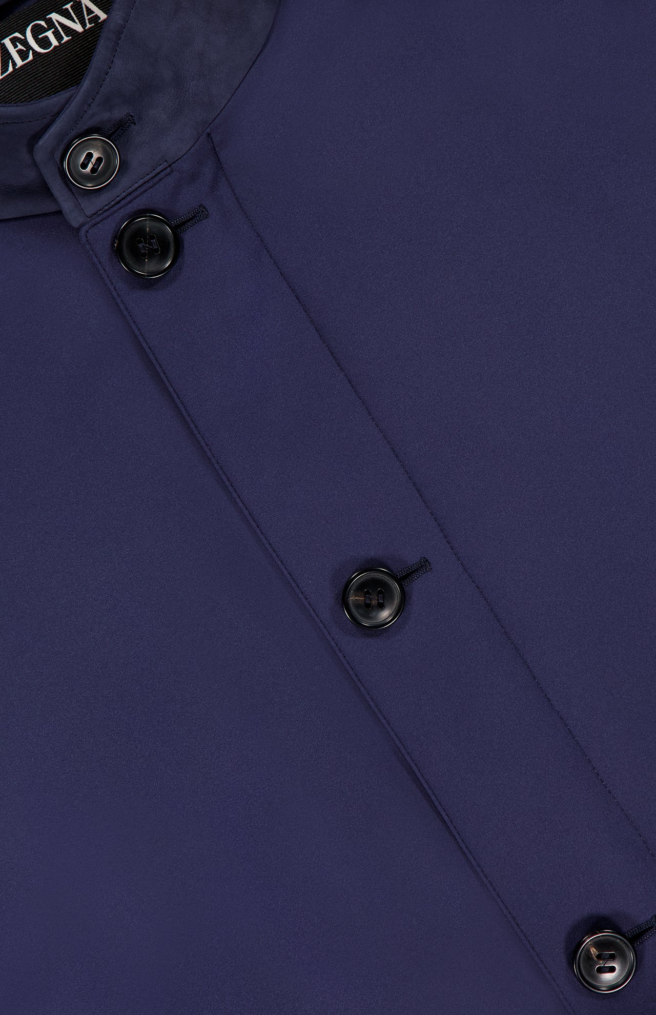 Close-up of a navy blue Microfiber Polyester Twill Vest by ZEGNA with black buttons and a leather collar. Part of the garment label displaying “ZEGNA” is visible at the top left.