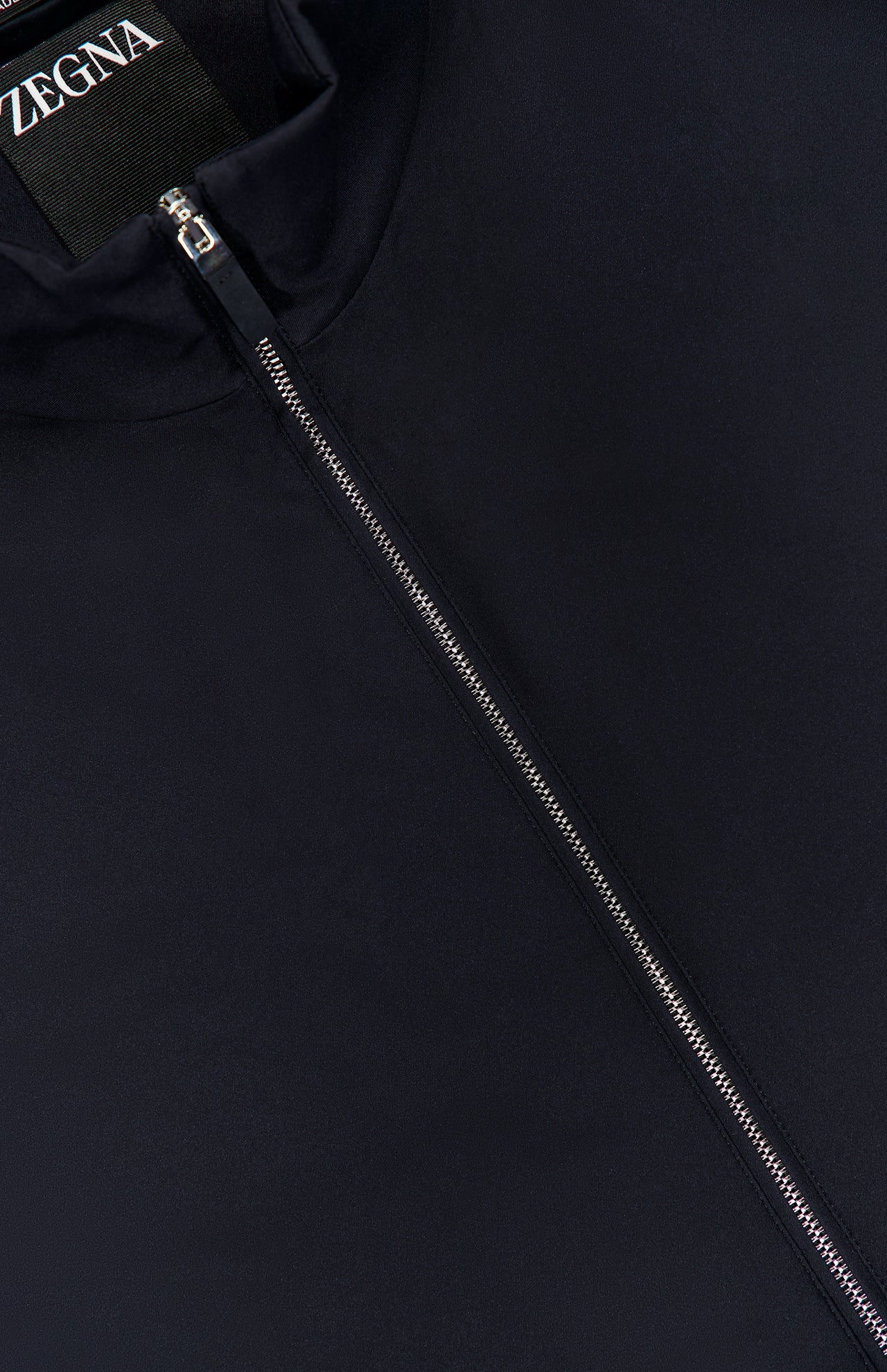 Close-up of the ZEGNA Motorin 2-way Zip Jacket in a dark minimalist design, featuring a silver zipper partially unzipped to reveal the ZEGNA label inside the collar.