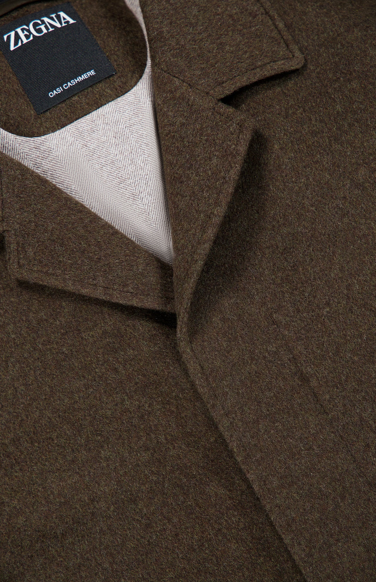 Close-up of a brown Oasi Cashmere Jacket by ZEGNA, showing the Zegna label on the inside collar, notched lapel, and light beige inner lining.