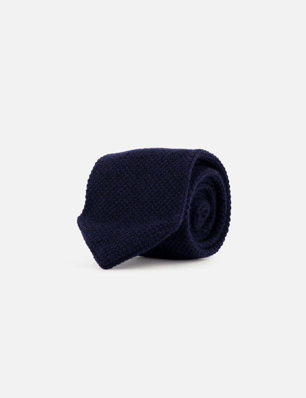 A rolled-up Oasi Cashmere Knit Tie in dark navy blue, featuring a refined knit design, is displayed on a plain light gray background. Expertly crafted in Italy by ZEGNA, this accessory embodies timeless elegance and superior craftsmanship.