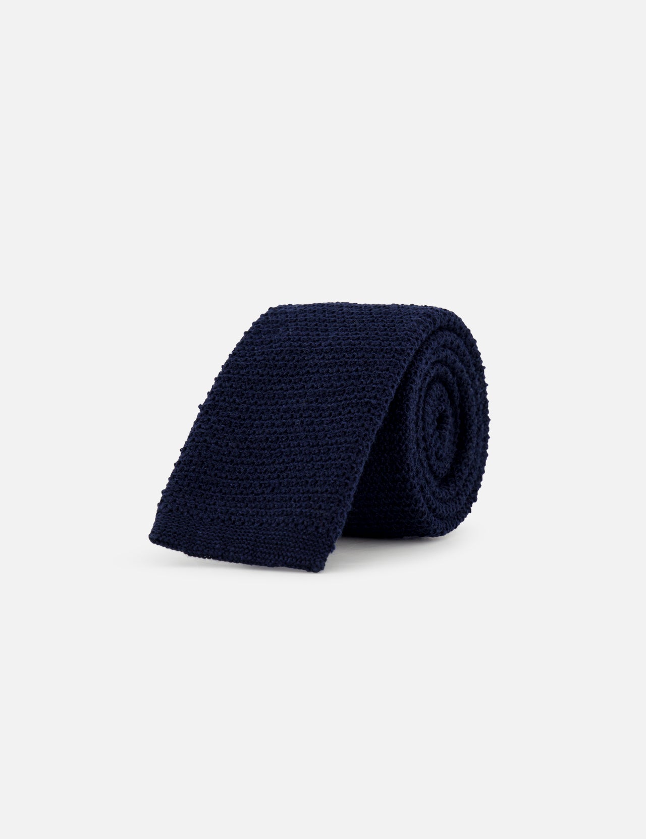 The ZEGNA Oasi Lino Knit Neck Tie for men, shown rolled up in dark navy blue, is displayed against a plain light grey background.