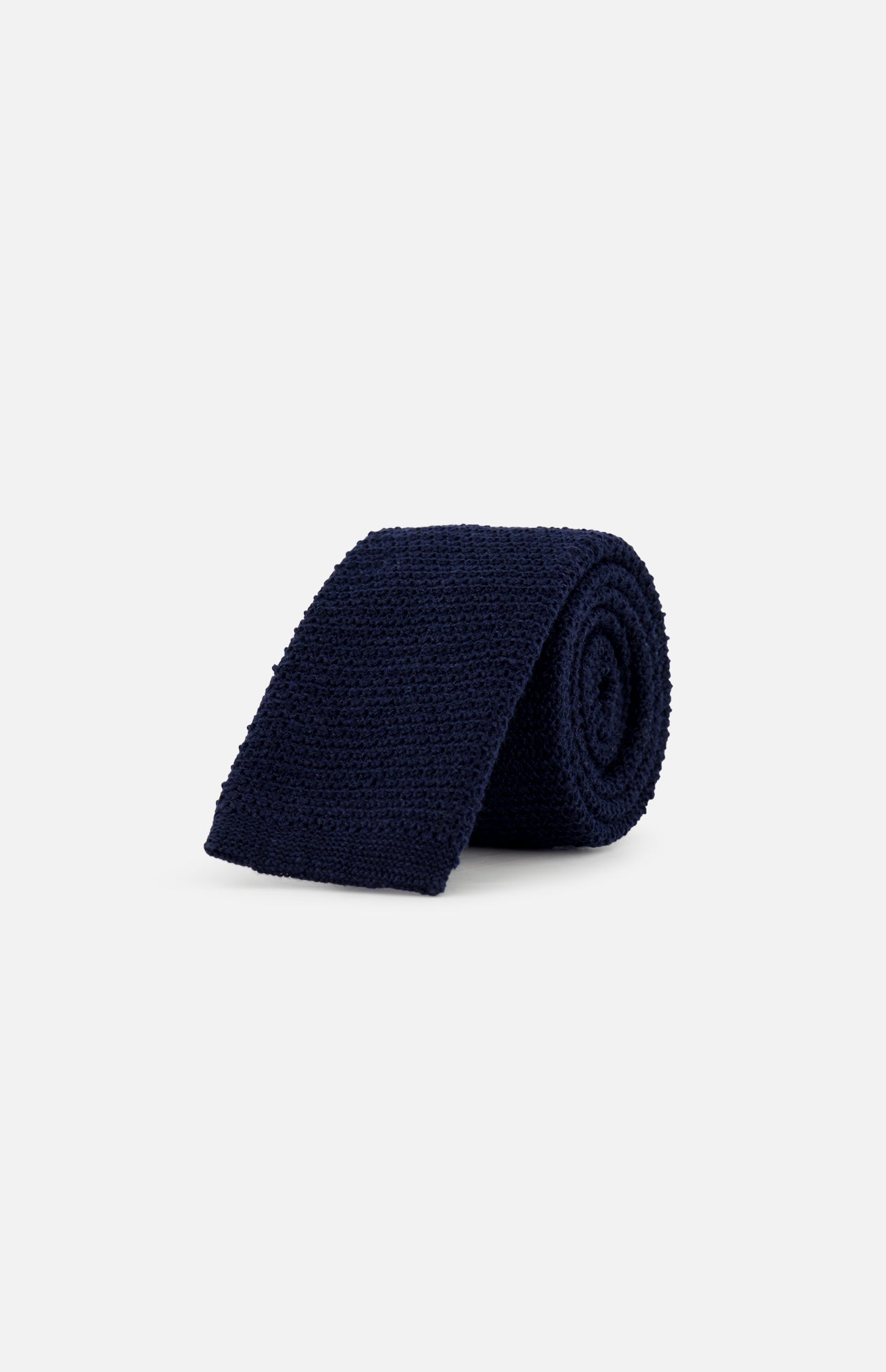 The ZEGNA Oasi Lino Knit Neck Tie for men, shown rolled up in dark navy blue, is displayed against a plain light grey background.