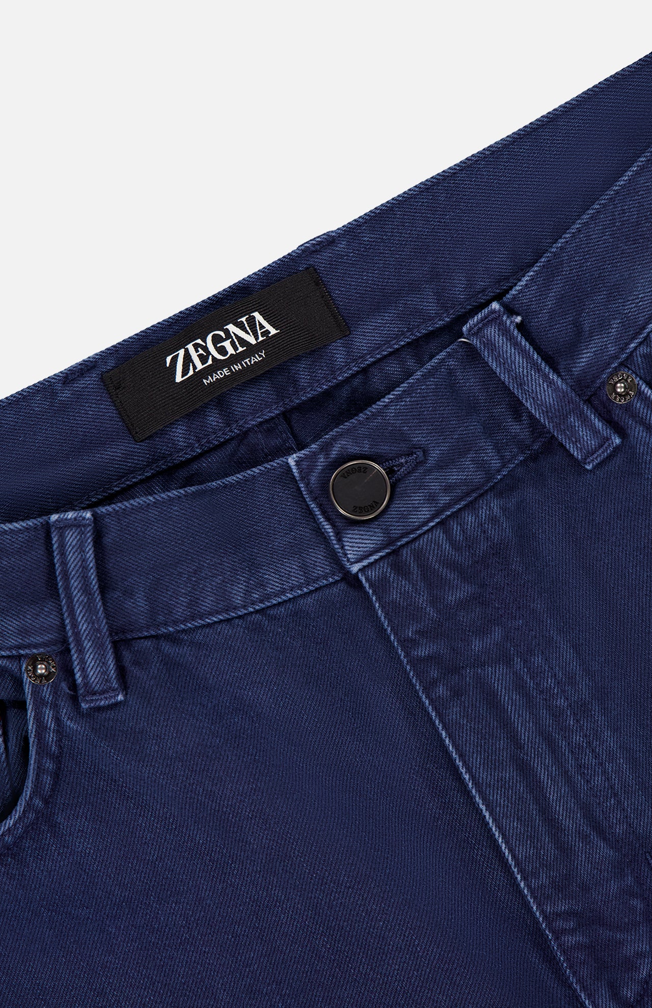Close-up of the waistband and upper front of ZEGNA Pure Cotton Slim Fit Pants in dark blue, featuring belt loops, a button closure, 5-pocket design, and a black ZEGNA label sewn inside the waistband.