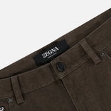 Close-up of Pure Cotton Slim Fit Pants by ZEGNA in brown corduroy with belt loops, black button, and a visible Zegna Made in Italy label on the waistband. Plain white background.