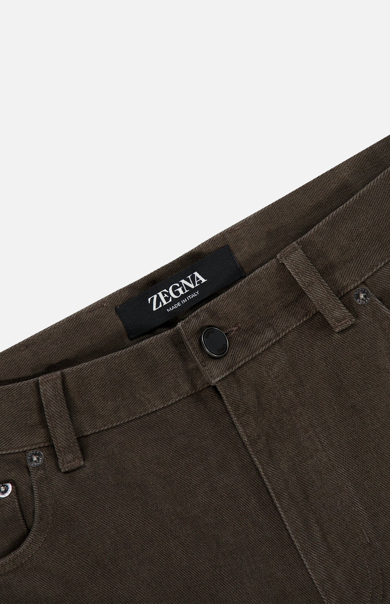 Close-up of Pure Cotton Slim Fit Pants by ZEGNA in brown corduroy with belt loops, black button, and a visible Zegna Made in Italy label on the waistband. Plain white background.