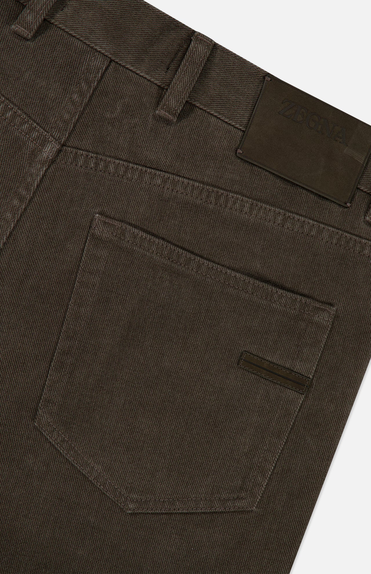 Close-up of the back pocket and waistband of ZEGNA Pure Cotton Slim Fit Pants in dark brown, with a black leather brand patch and belt loops for vintage workwear appeal.