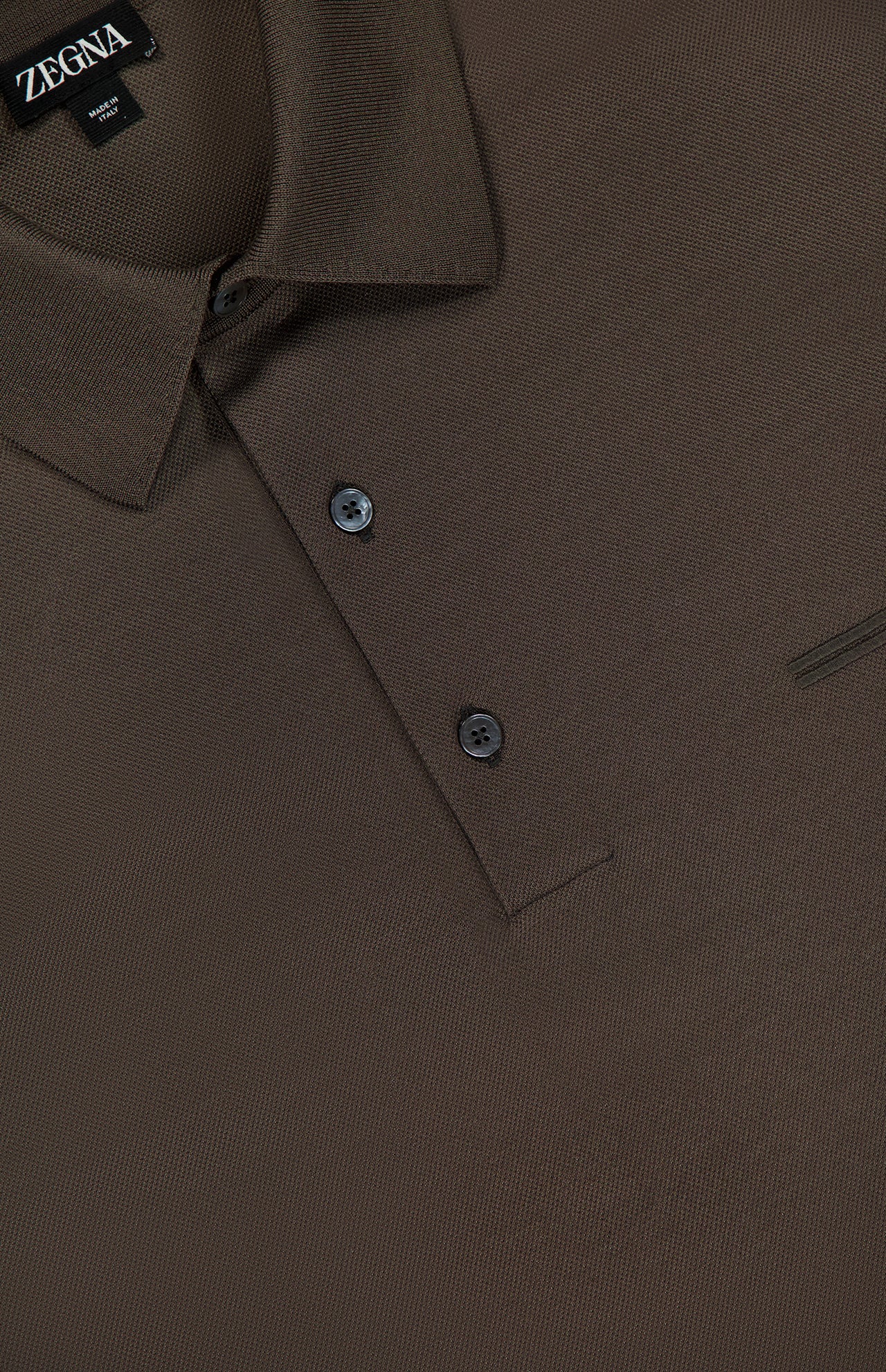 Close-up of a ZEGNA Pure Cotton Short Sleeve Polo Shirt in brown, highlighting the textured fabric, collar, chest pocket detail, two buttons, and brand label inside the neckline. Made in Italy.
