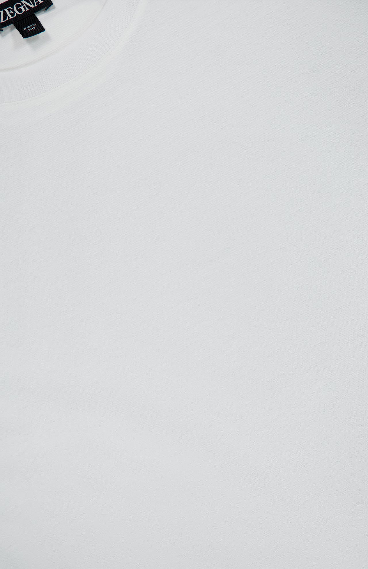 Close-up of a Pure Cotton T-Shirt by ZEGNA, featuring a plain white crew neck in 100% cotton with a black label at the neckline.