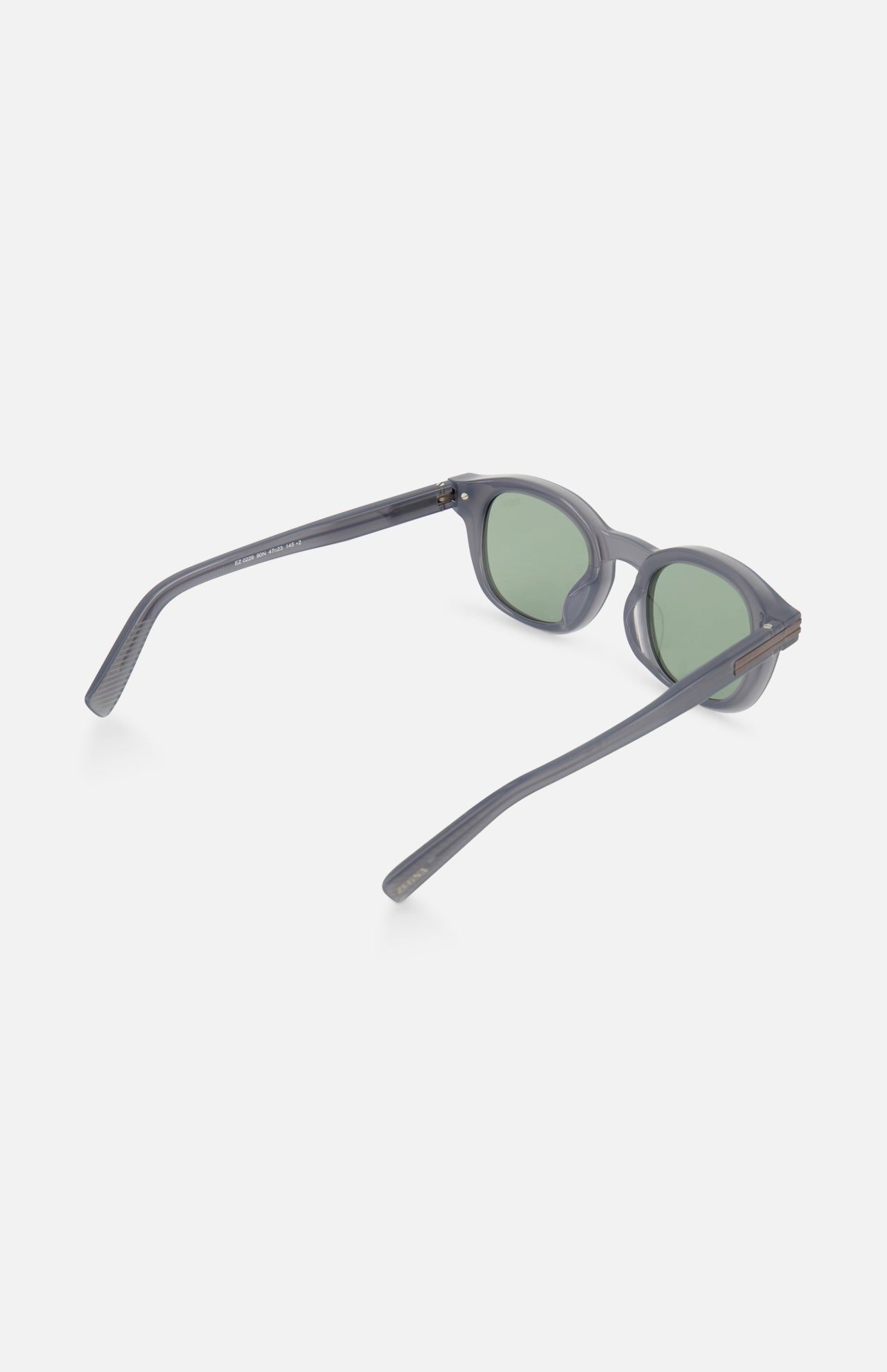 Rounded light blue ZEGNA sunglasses featuring round frames and green tinted lenses, displayed at an angle from the side and slightly above to show the open arms and inner sides of the frame.