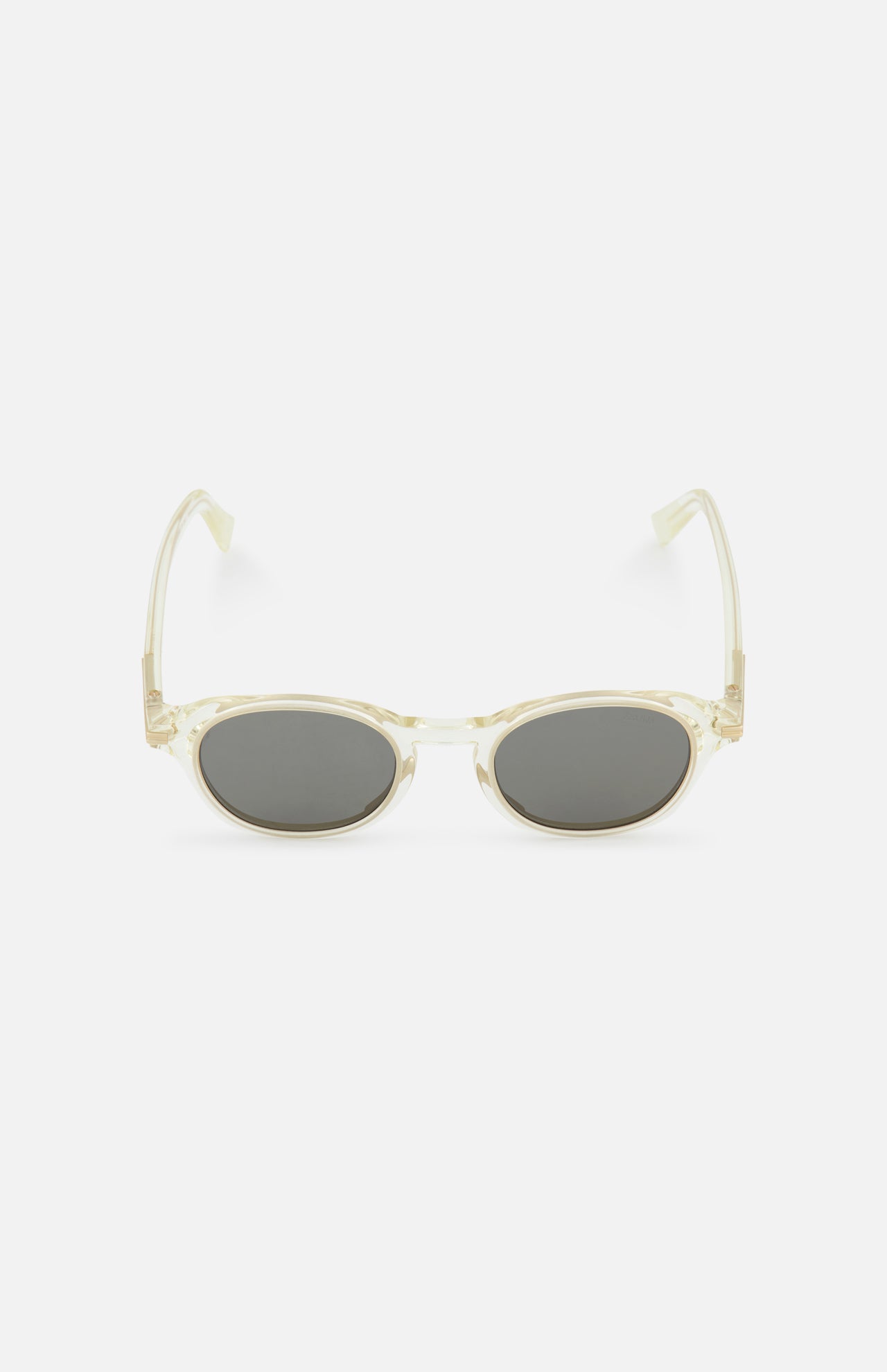 ZEGNA Rounded Champagne Sunglasses feature a transparent, retro-inspired oval frame with thick arms and smoke lenses, shown front-facing on a plain white background.