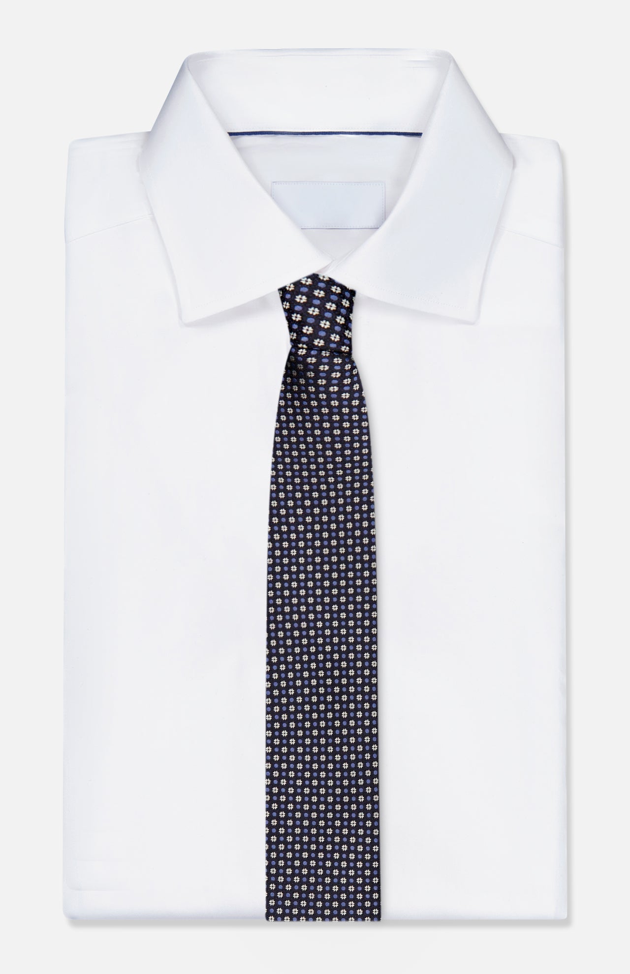 A neatly folded white dress shirt with a crisp collar is paired with the ZEGNA Silk Jacquard Tie, an elegant blue silk accessory made in Italy and detailed with a refined pattern of small, light-colored dots. The ensemble is presented against a plain white background.