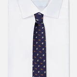 A neatly folded white dress shirt is paired with the ZEGNA Silk Jacquard Tie, a luxurious dark blue accessory made in Italy and featuring a small, repeating pattern of brown and light blue leaf shapes.
