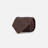 A rolled-up ZEGNA Silk Jacquard Tie in dark brown with a subtle checkered pattern, crafted in Italy, displayed on a plain white background.