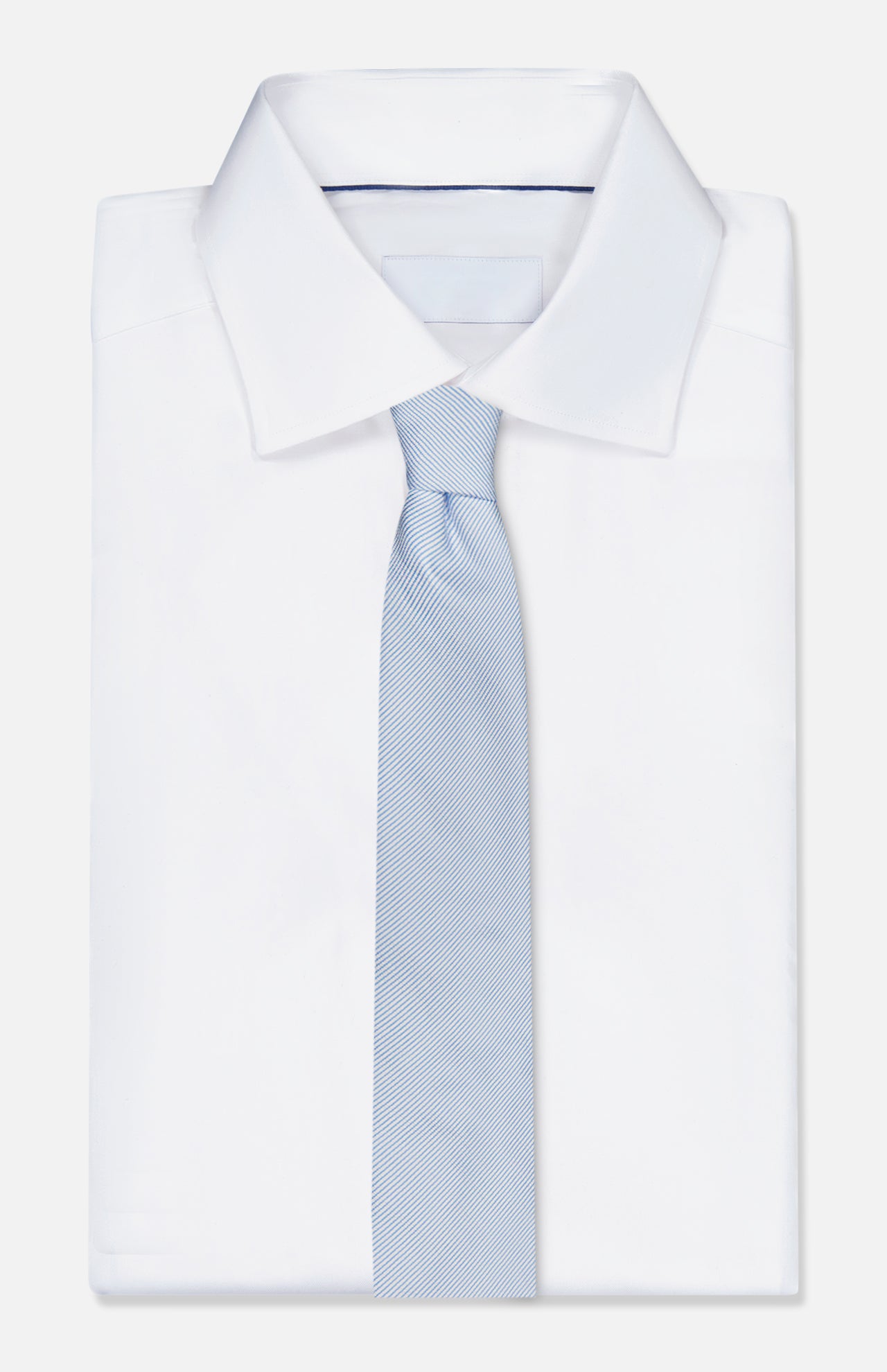 A ZEGNA Silk Jacquard Neck Tie in light blue is styled down the center of a neatly folded white dress shirt with a pointed collar, displayed on a plain white background.