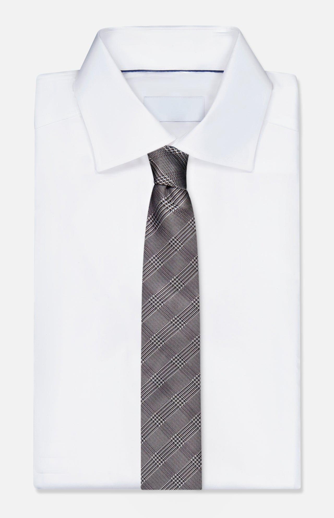 A neatly folded white dress shirt with a classic collar is paired with the ZEGNA Silk Jacquard Tie in grey and black, crafted in Italy, and displayed against a plain white background.