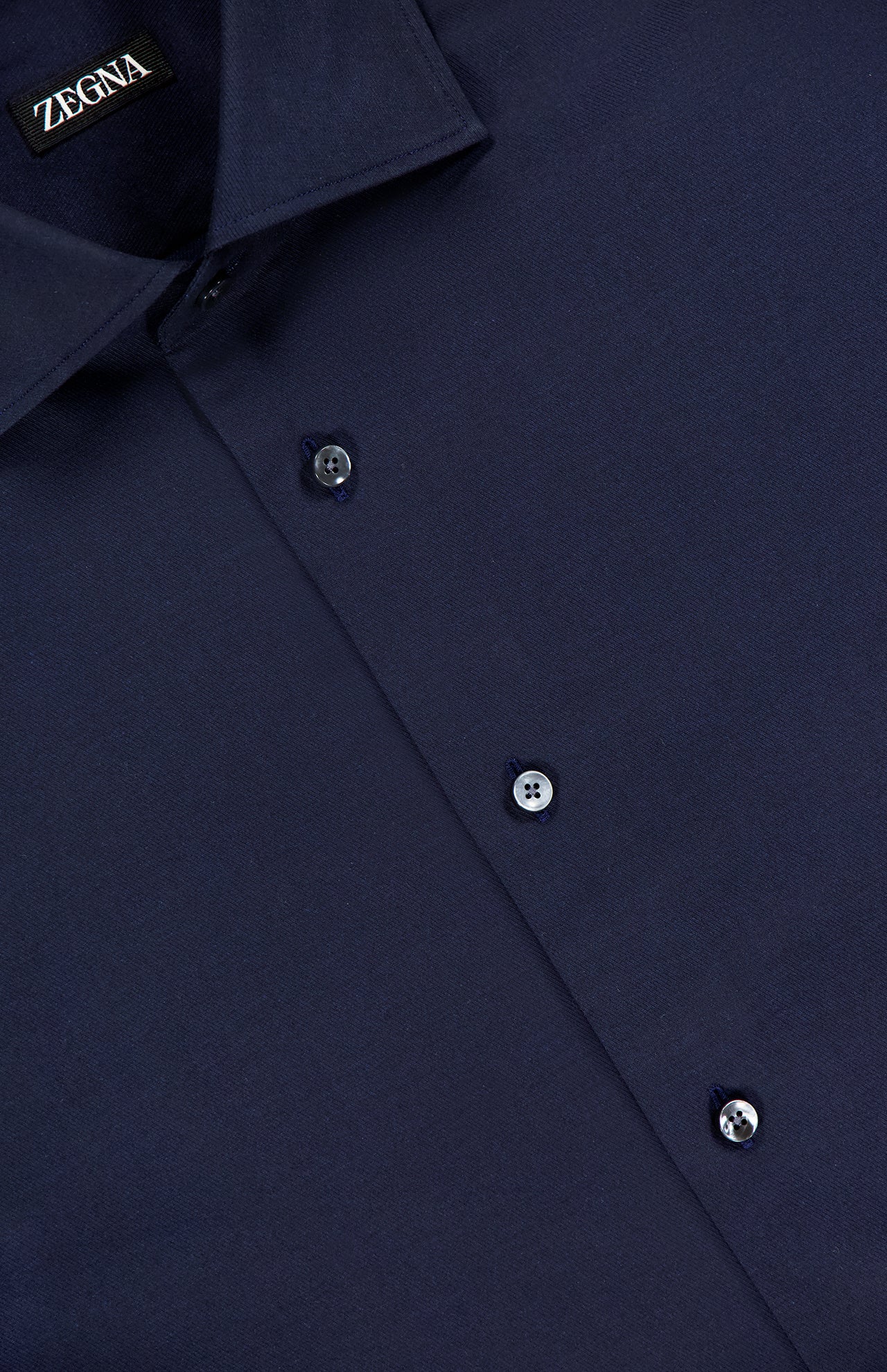 A close-up of ZEGNA’s Stretch Cotton Dress Shirt in navy, crafted from smooth, finely woven stretch cotton, highlights the collar and three front buttons—an essential piece for any professional wardrobe.