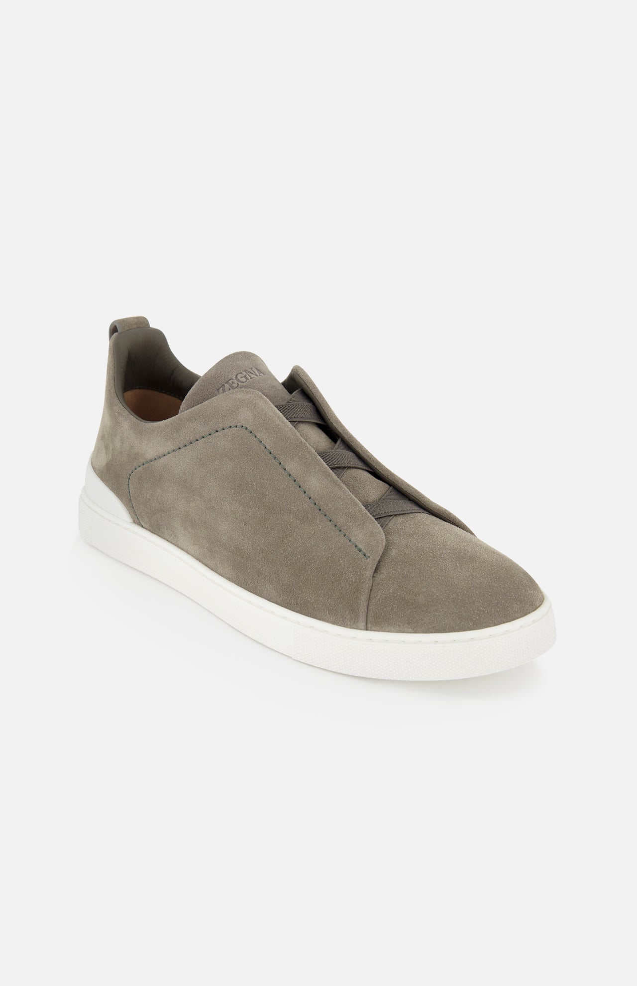 The ZEGNA Triple Stitch Low Top Sneaker features a grey suede slip-on design with a white rubber sole and minimalist look, epitomizing luxury casual footwear, shown on a plain white background.