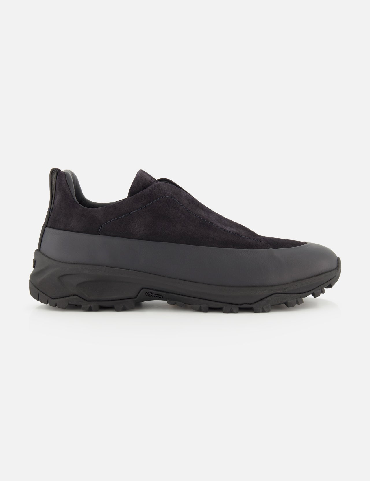 The ZEGNA Triple Stitch Low Top Sneaker is a black slip-on shoe with a rugged rubber sole and a durable leather and suede upper, displayed in side profile against a white background; this hiking-inspired sneaker offers the easy wear of a slip-on combined with lasting craftsmanship.