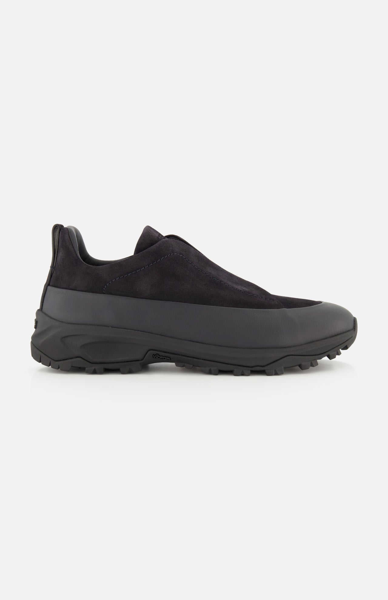The ZEGNA Triple Stitch Low Top Sneaker is a black slip-on shoe with a rugged rubber sole and a durable leather and suede upper, displayed in side profile against a white background; this hiking-inspired sneaker offers the easy wear of a slip-on combined with lasting craftsmanship.