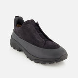 The ZEGNA Triple Stitch Low Top Sneaker is a black, hiking-inspired slip-on with a suede upper and minimal detailing, set atop a thick rubber sole. The shoe is photographed against a plain white background.