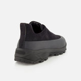 The ZEGNA Triple Stitch Low Top Sneaker is a black, hiking-inspired shoe with a slip-on design, featuring a thick, rugged sole and a smooth upper. It is displayed from the rear angle on a plain white background.