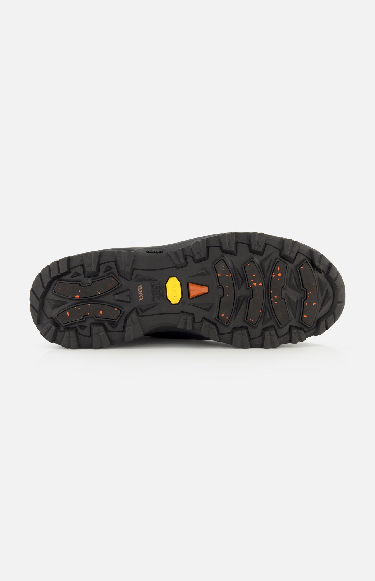 The image shows the black rubber sole of the ZEGNA Triple Stitch Low Top Sneaker, a black hiking-inspired shoe with deep treads and orange and yellow accents, designed for enhanced grip and traction.