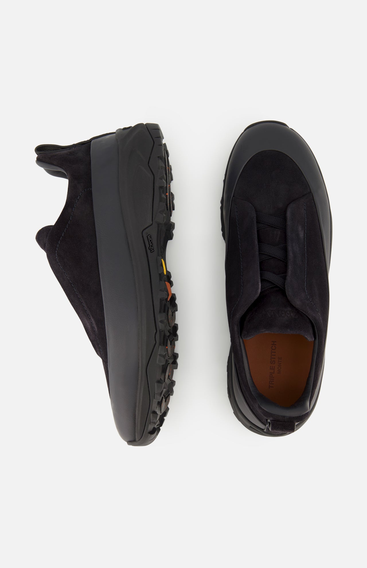 A pair of ZEGNA Triple Stitch Low Top Sneakers in black leather and suede, featuring chunky black soles, is displayed from the side and top views against a plain white background.