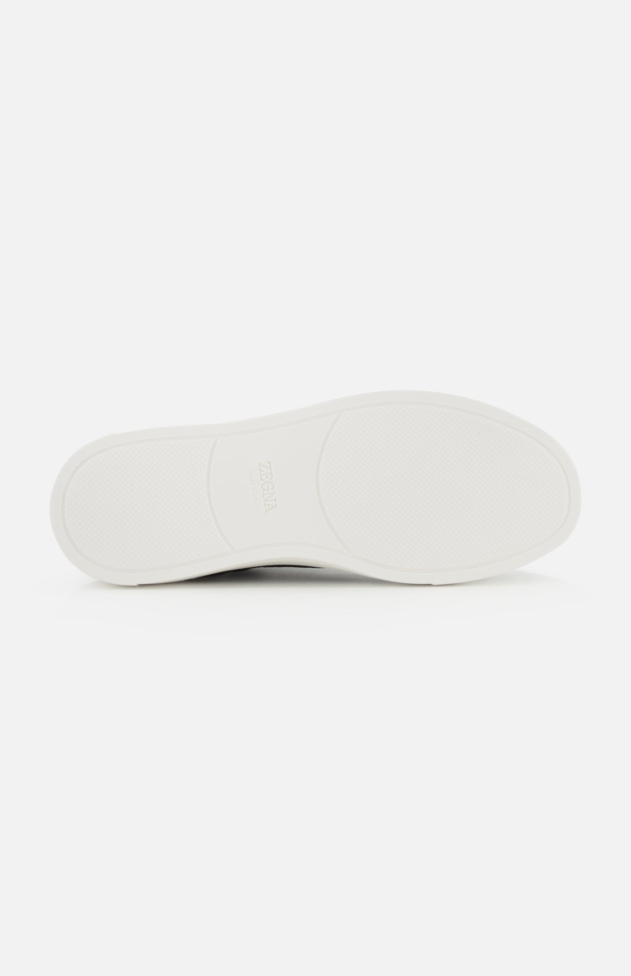 Flat white rubber sole of a ZEGNA Triple Stitch Low Top Sneaker, featuring a textured tread pattern and a logo at the center.