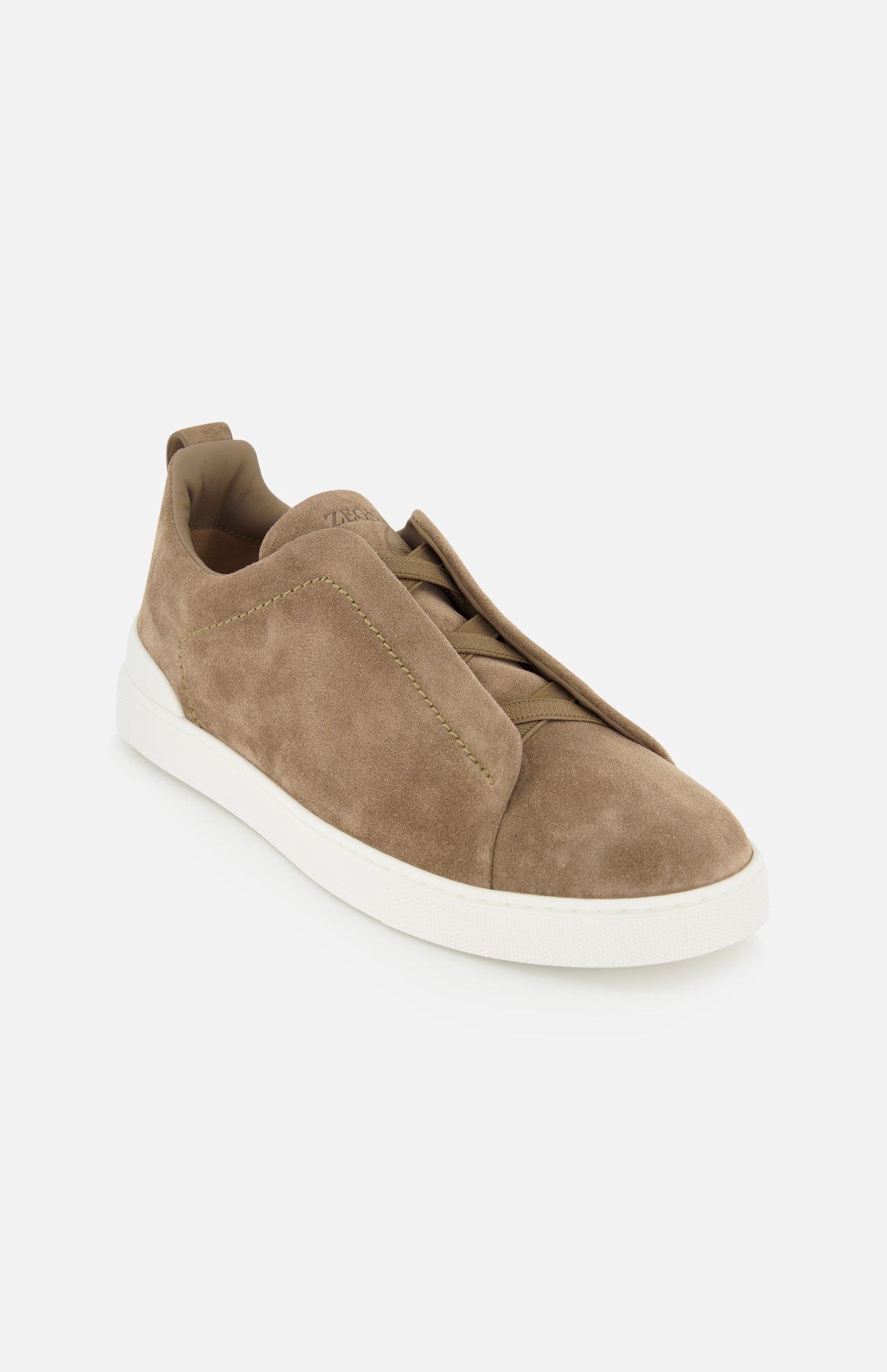 The ZEGNA Triple Stitch Low Top Sneaker features brown suede in a slip-on design with a white rubber sole and minimal stitching details inspired by luxury casual footwear, photographed against a plain white background.
