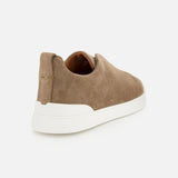 A luxurious casual footwear choice, the tan suede ZEGNA Triple Stitch Low Top Sneaker is showcased from the back and slightly to the side against a plain white background, highlighting its sleek white rubber sole.