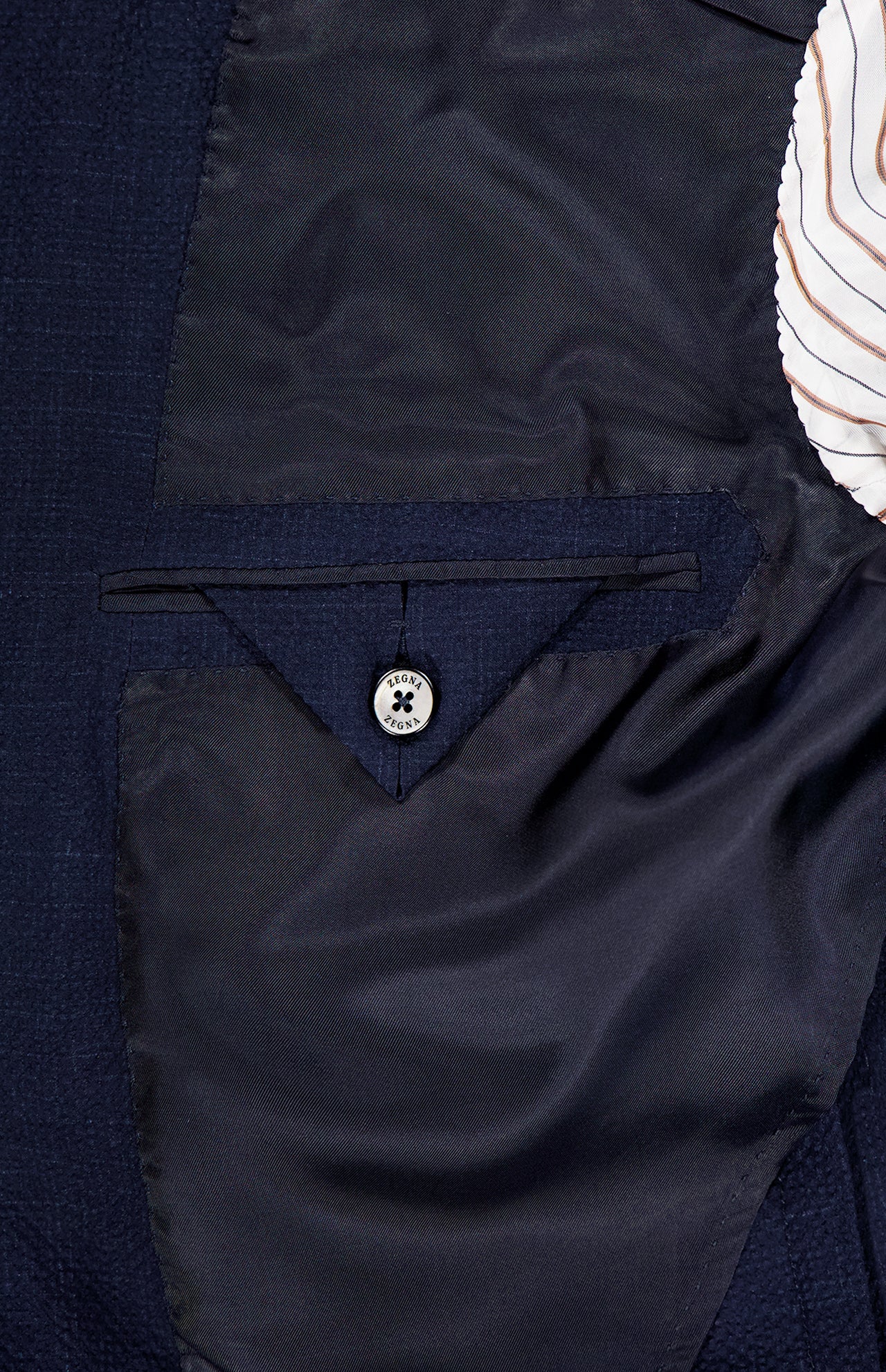 Close-up of the ZEGNA Trofeo Seersucker Suit Jacket’s interior, featuring a buttoned pocket with dark stitching and partially visible striped lining at the top right.