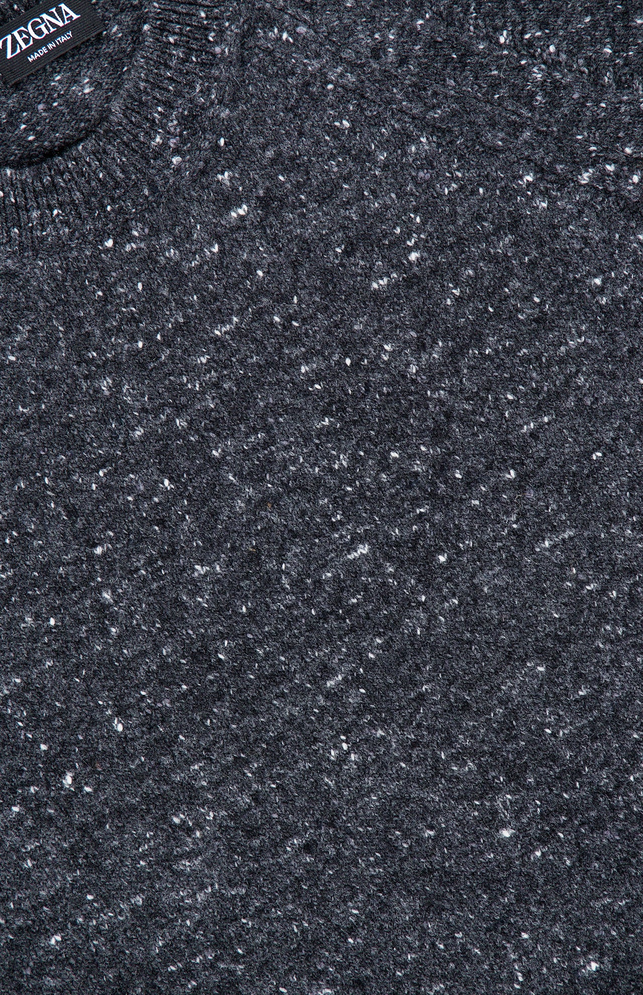 Close-up of the Wool & Cashmere Blend Crewneck Sweater in dark grey, showcasing its subtle speckled knit texture. Expertly crafted from a luxurious wool and cashmere blend, this men’s pullover features a visible corner of the ZEGNA label in the top left, highlighting its distinguished brand.