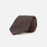 A ZEGNA Wool & Silk Jacquard Tie in dark brown is rolled up and displayed on a plain white background. Expertly crafted in Italy, this textured necktie exudes timeless elegance.