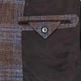 Close-up of the interior of the ZEGNA Wool Silk Linen Sportcoat in brown plaid, featuring a pocket with a flap and button, set against a dark brown silky lining.