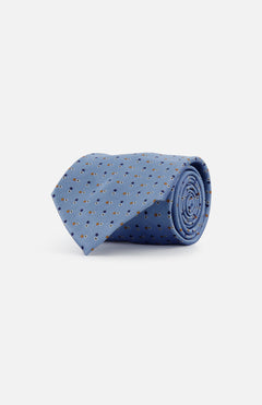 The ZEGNA Silk Dots Jacquard Tie, crafted in Italy, features a pale blue silk with a refined dark blue and brown floral pattern and is shown rolled up on a plain white background.