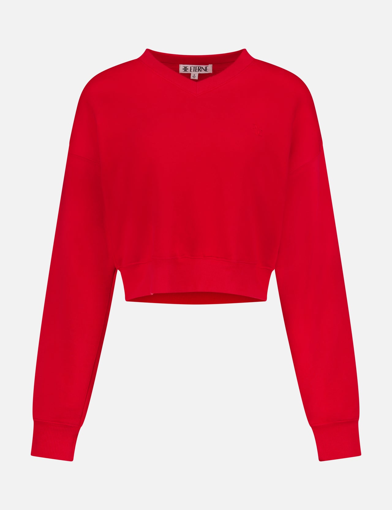 The ETERNE Cropped V-Neck Sweatshirt features a bright red hue, long sleeves, soft French terry fabric, ribbed cuffs, and a small logo tag at the back neck, displayed on a plain white background.
